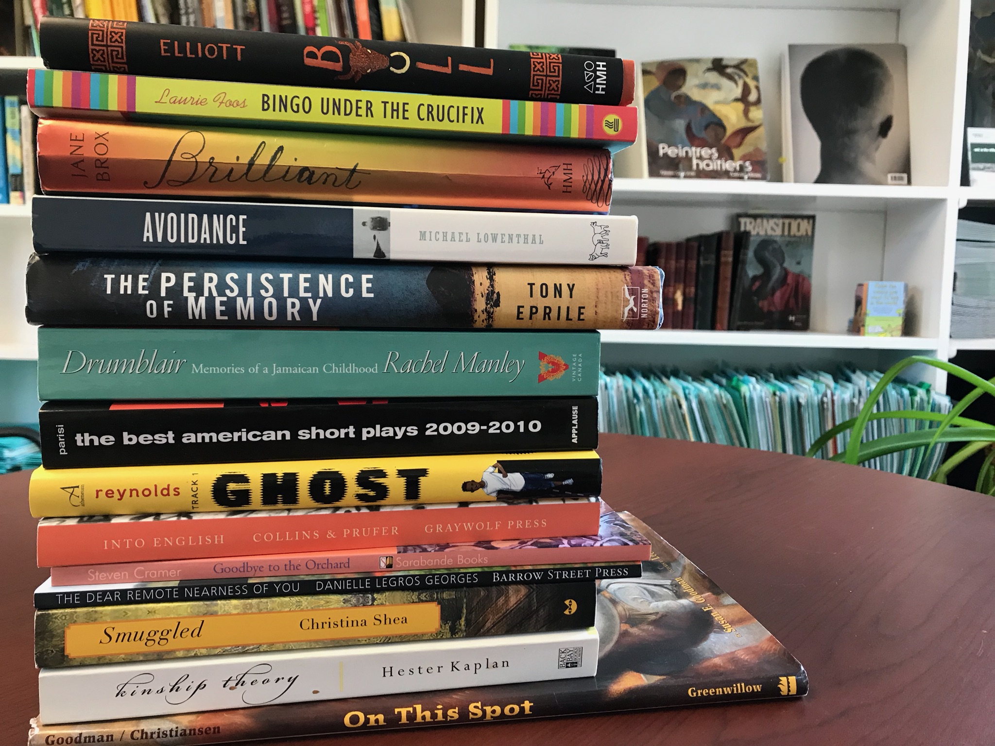 Stack of books on a table with white shelving in the background