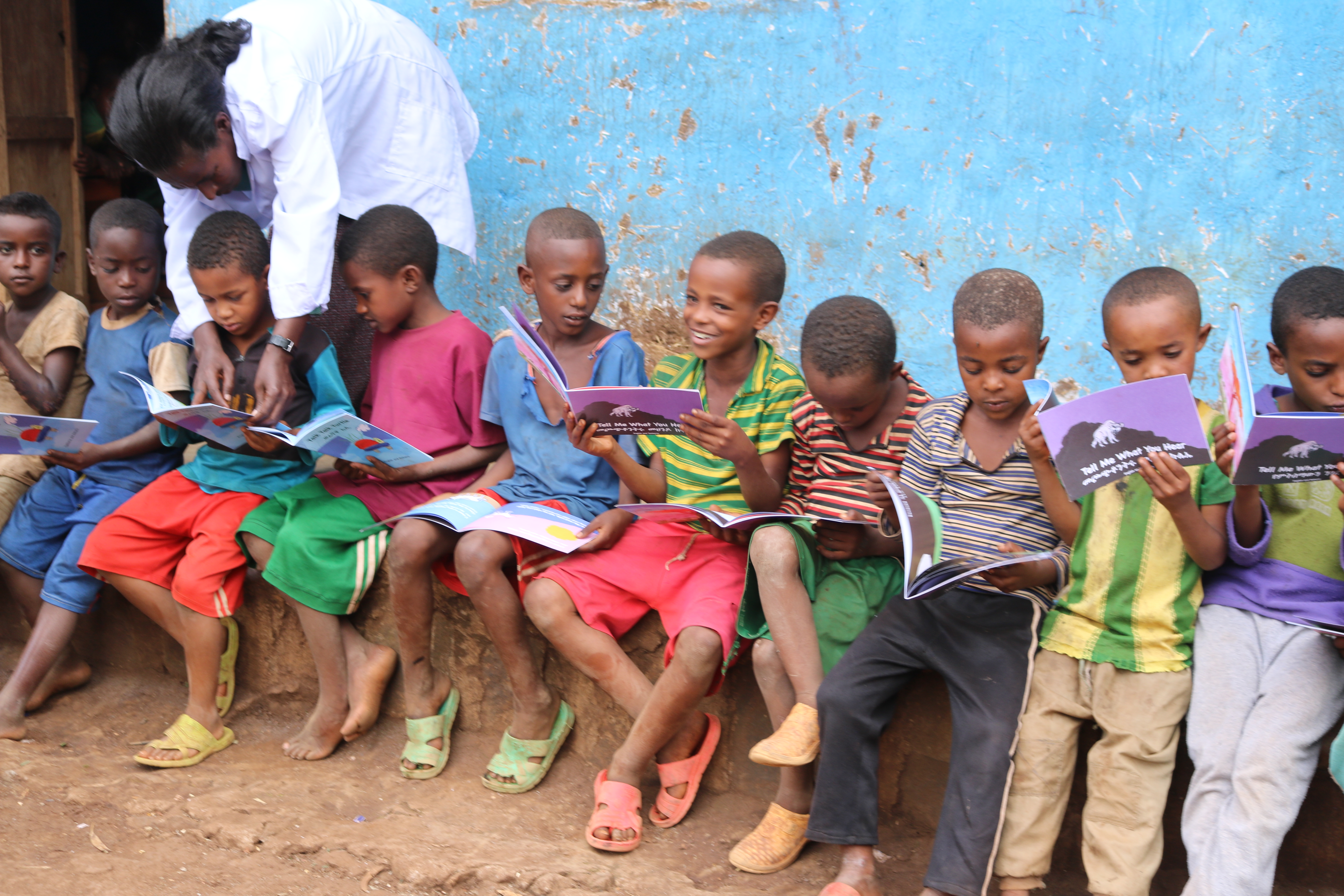 Children sitting outside on a sidewalk in Ethiopia with their science books.