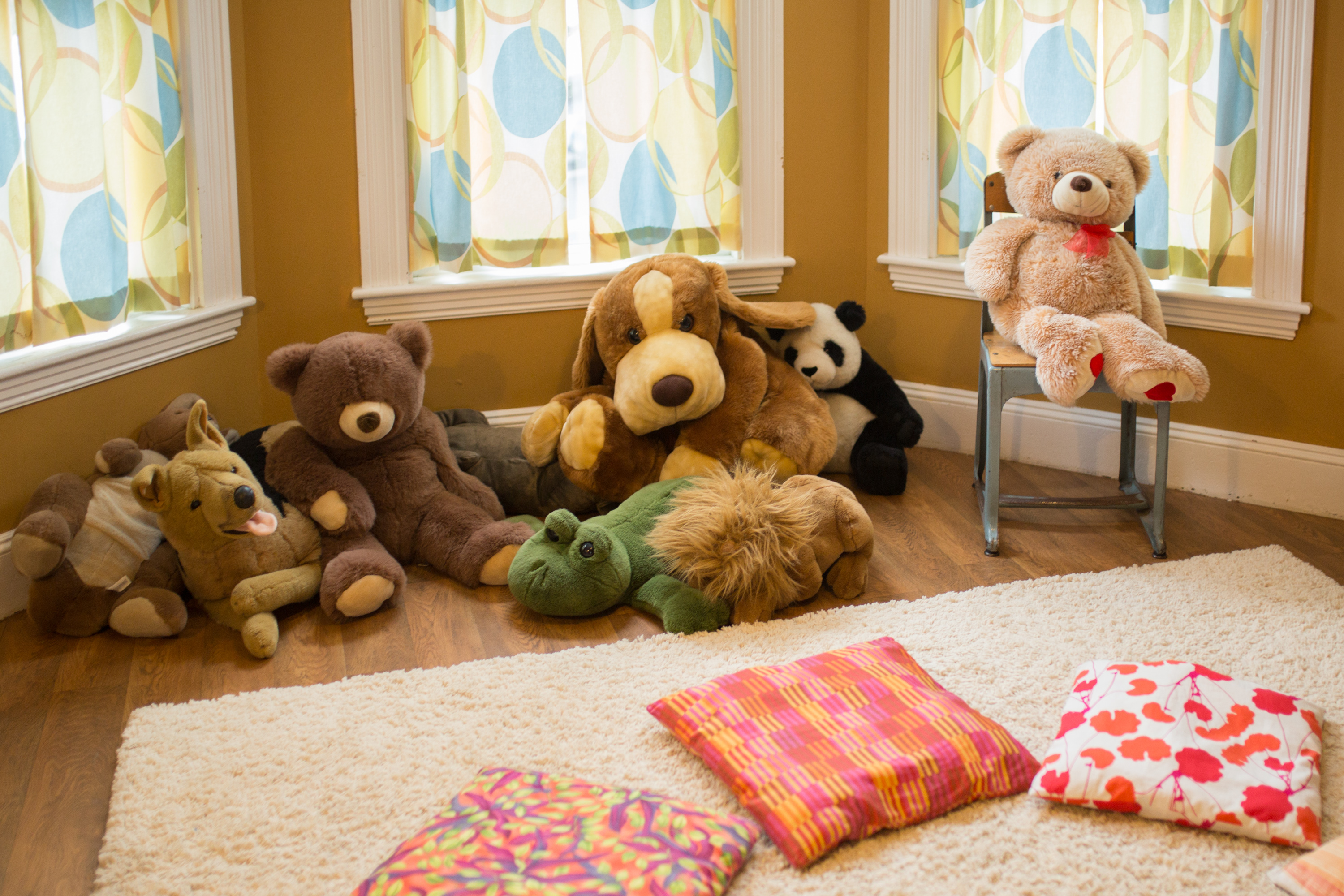 A room with teddy bears and floor pillows.