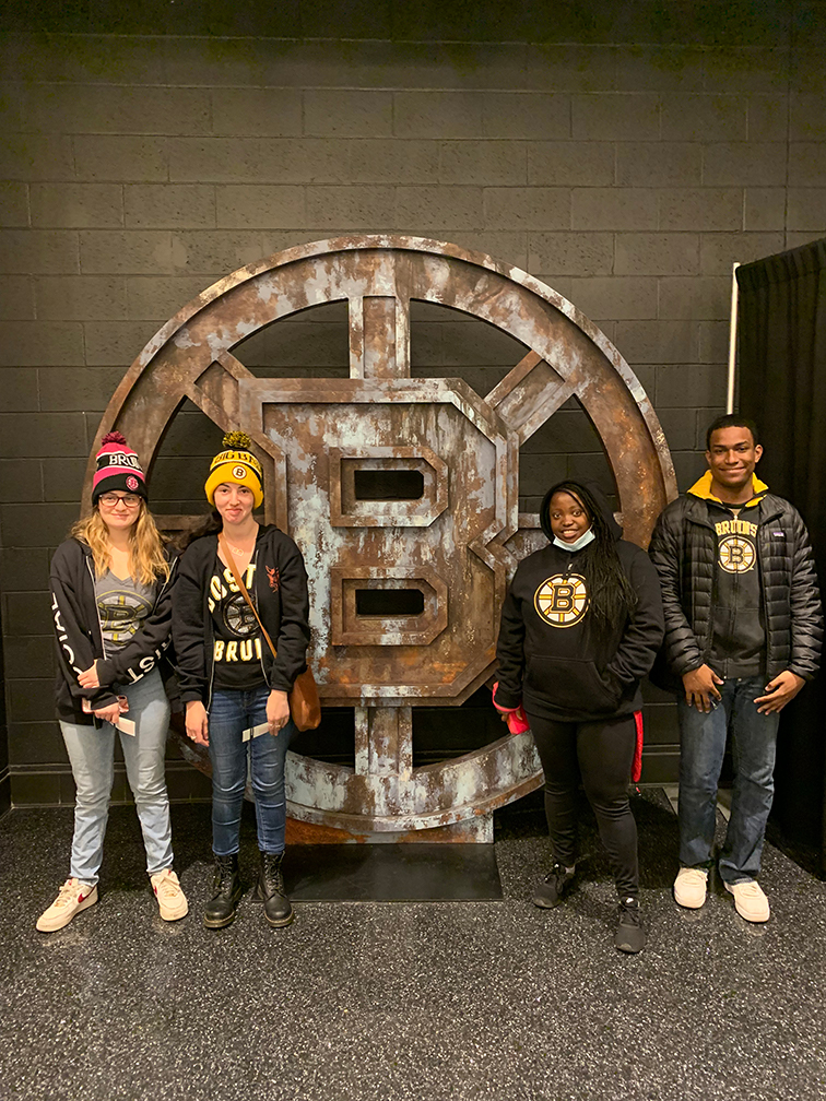 Threshold students Casey Robinson, Bella Coven, Demi Muhorakeye and Sebastien Roland enjoy a field trip to a Bruins game. They are pictured standing in front of a statue of the Bruins logo at TD Garden.