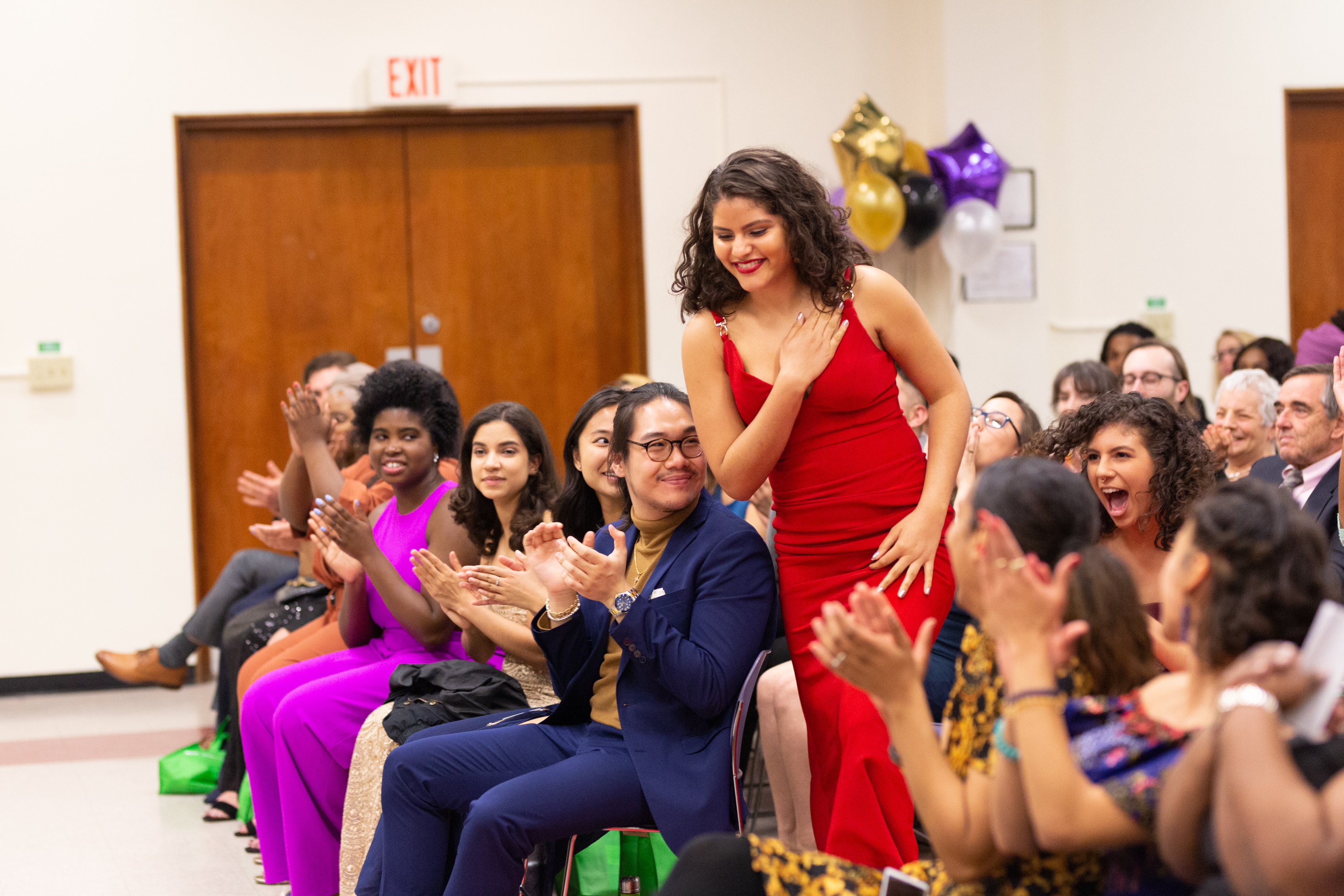 Woman in a red gown stepping out of the audience to receive an award at the Unity Gala.