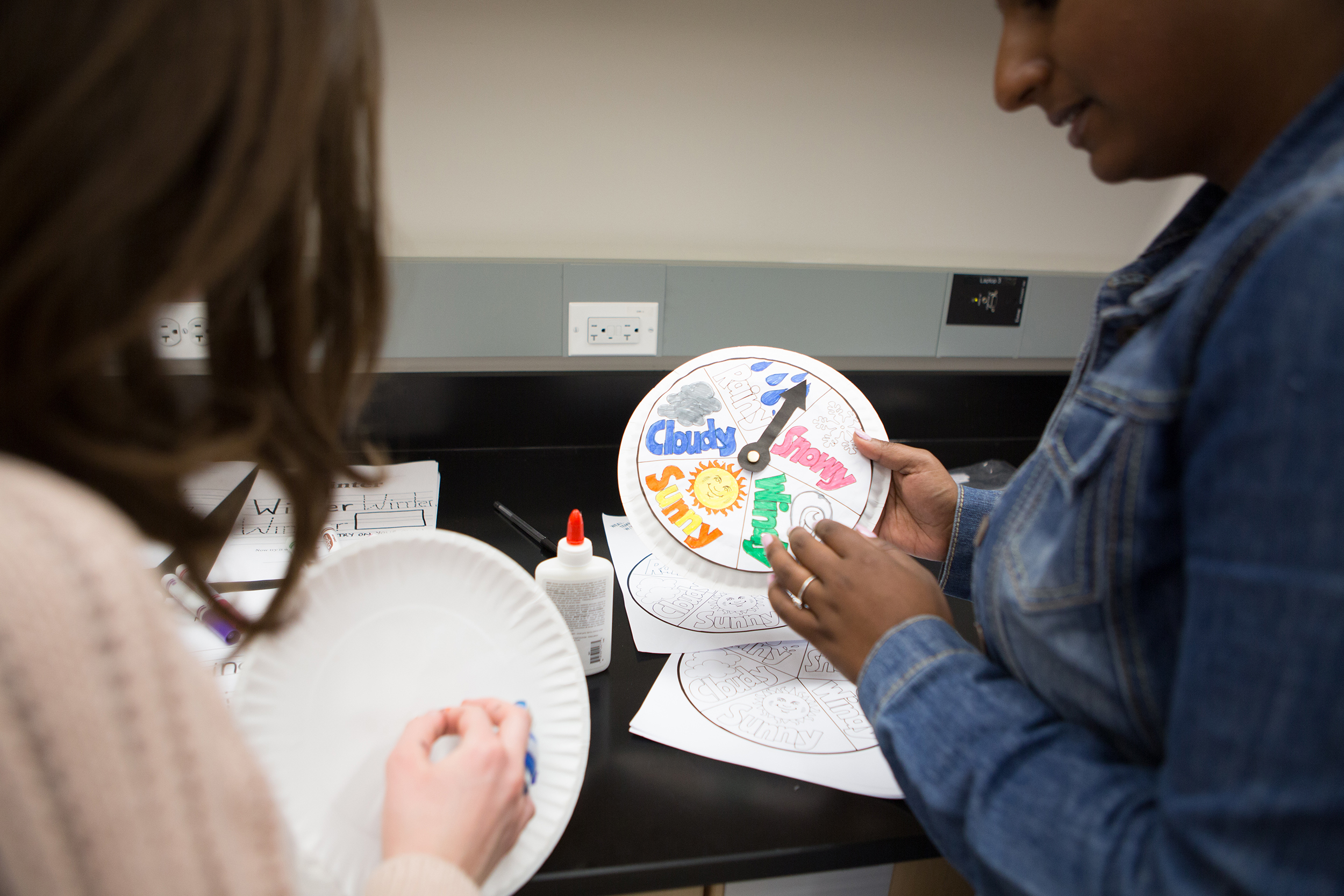 Lesley student holding a weather chart created on paper plate