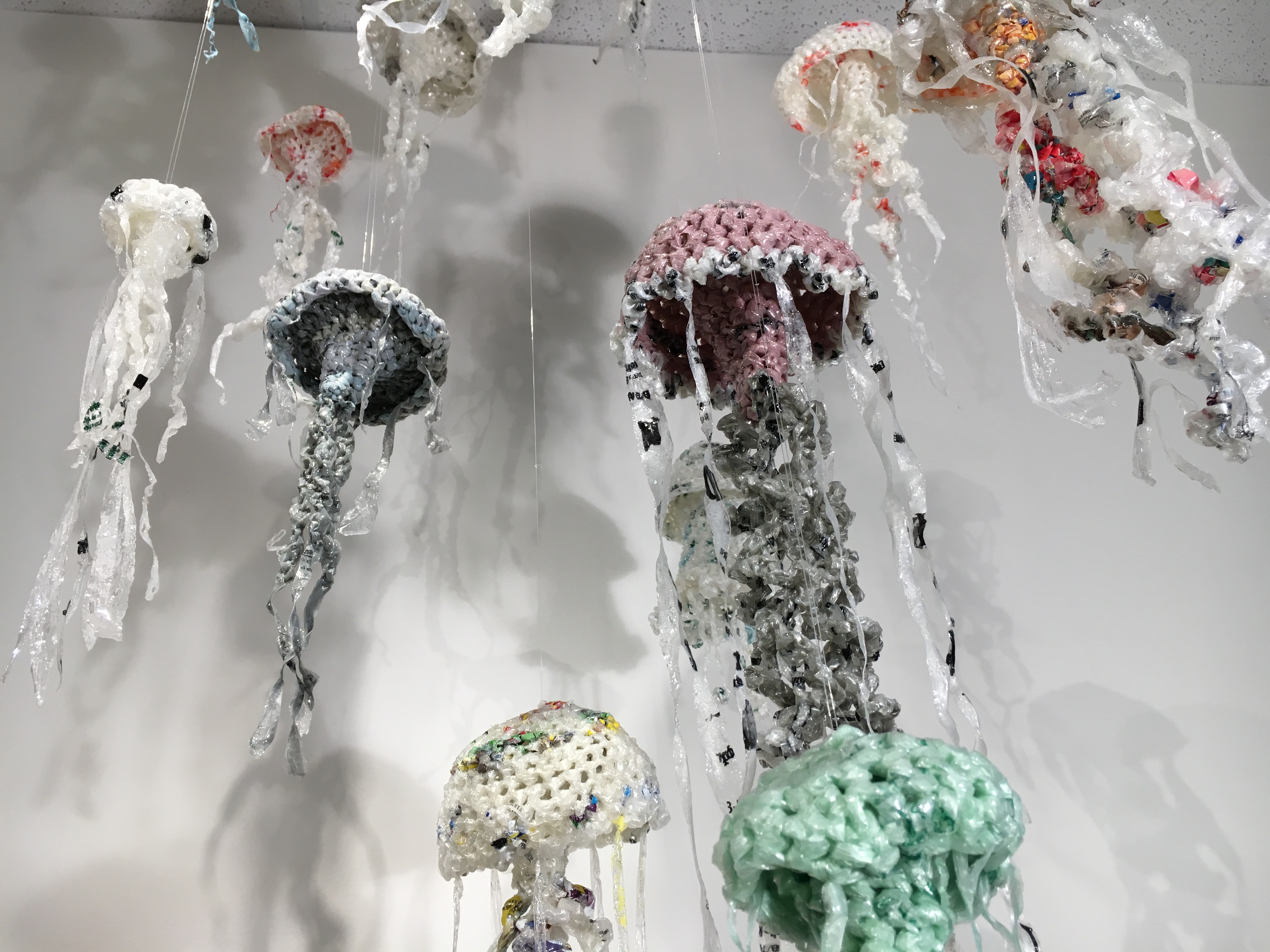 Jellyfish sculptures made of plastic hang from a ceiling