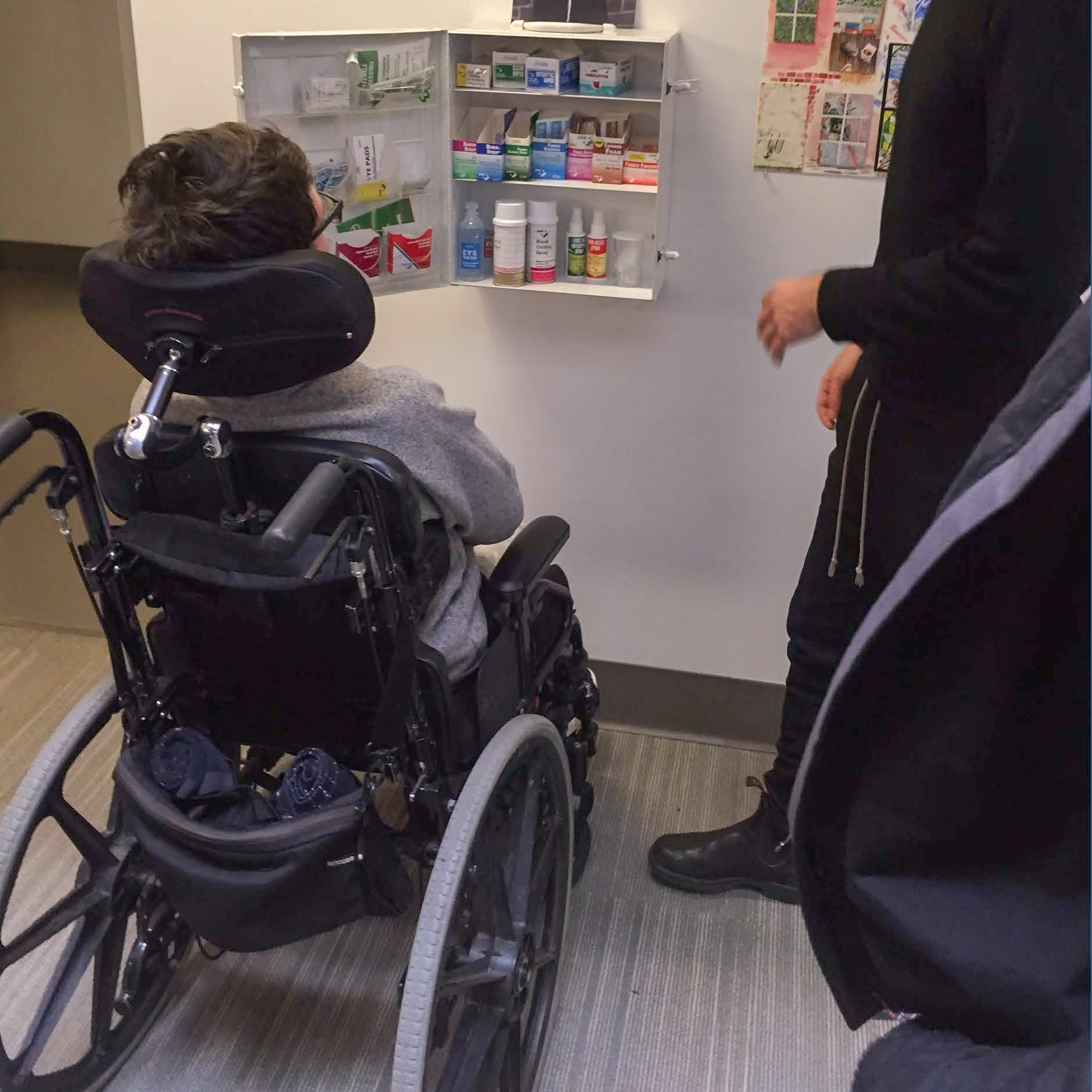 student in wheelchair accessing first-aid kit on wall