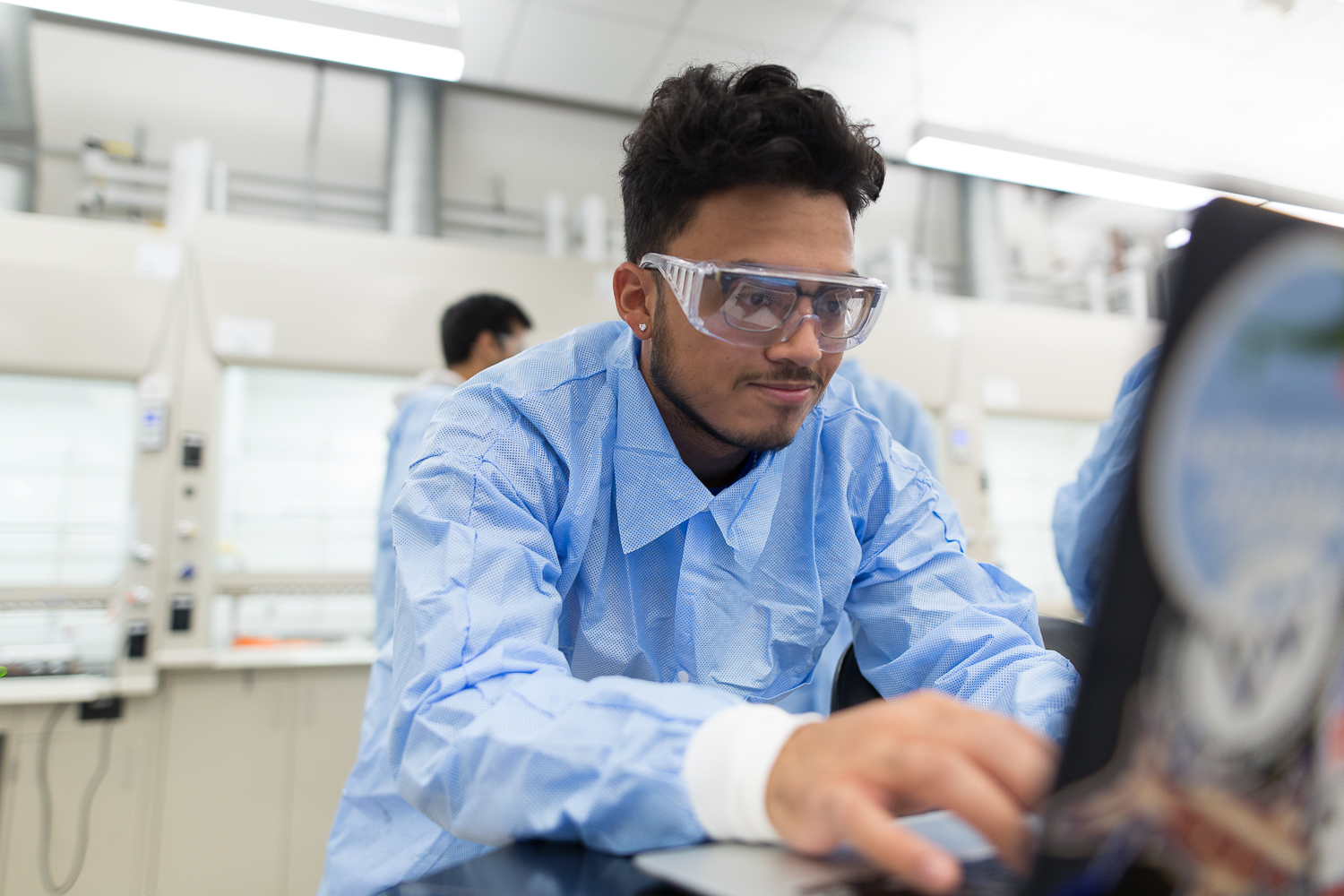 A close up of a student in the lab with protective glasses on. 