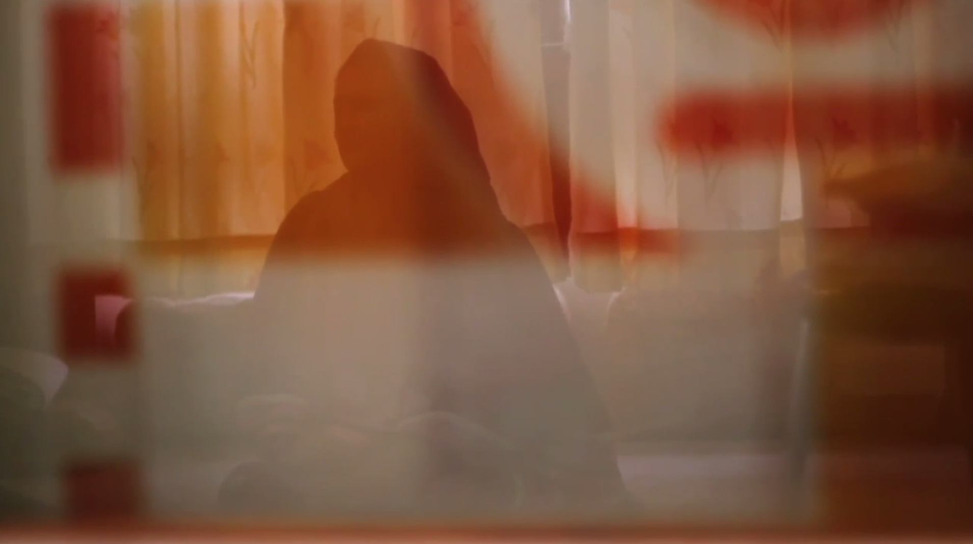Silhouette of an unidentifable woman behidn a curtain.