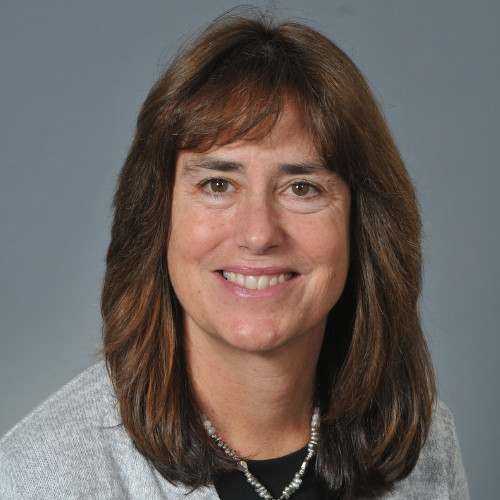 Photo of Stacey smiling against a gray background