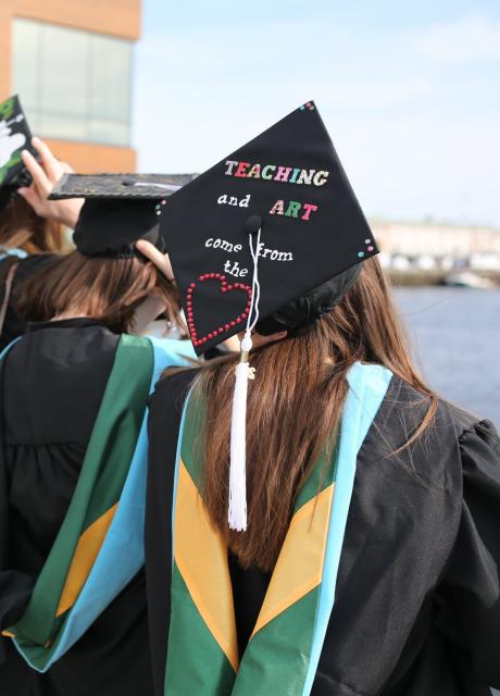 students lined up for commencement with backs of decorated hats showing