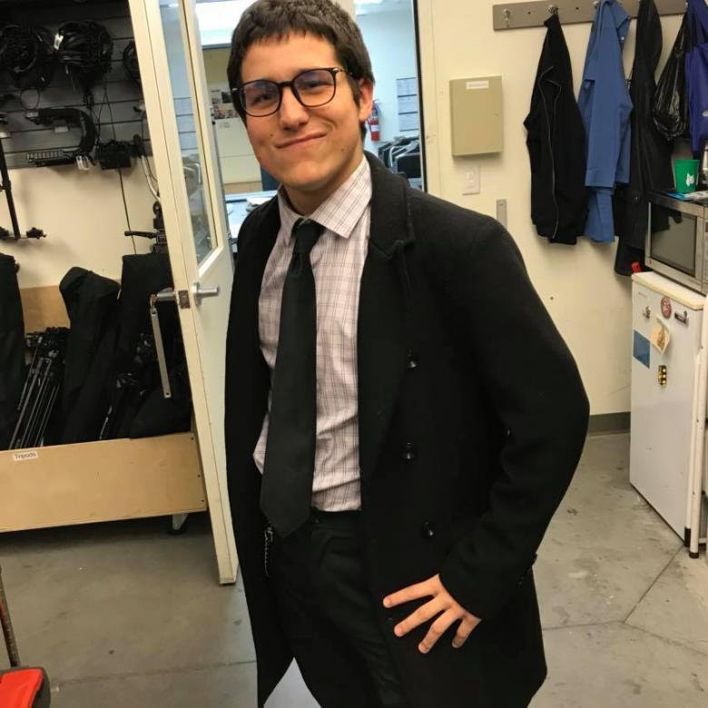 student poses in office wearing a suit and tie