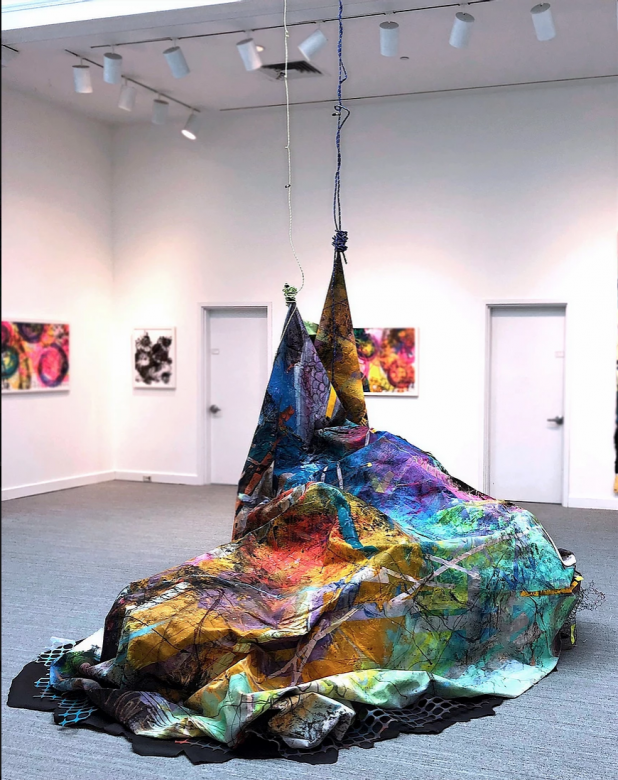multicolored tapestry suspended from gallery ceiling 