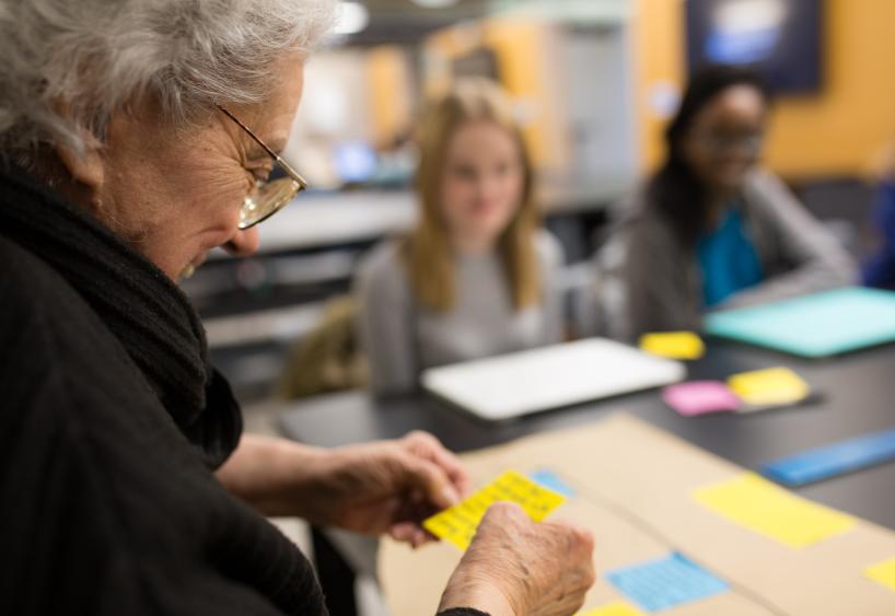 woman looks at sticky notes at a table with students