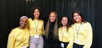 Four volunteers in yellow T-shirts flank actress Amanda Seales, dressed in all black