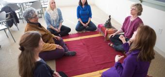 Group of women kneeling in a circle on the floor in a mindful meditation graduate class