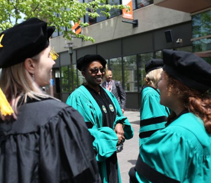 PhD students outside in caps and robes, about to attend their hooding ceremony