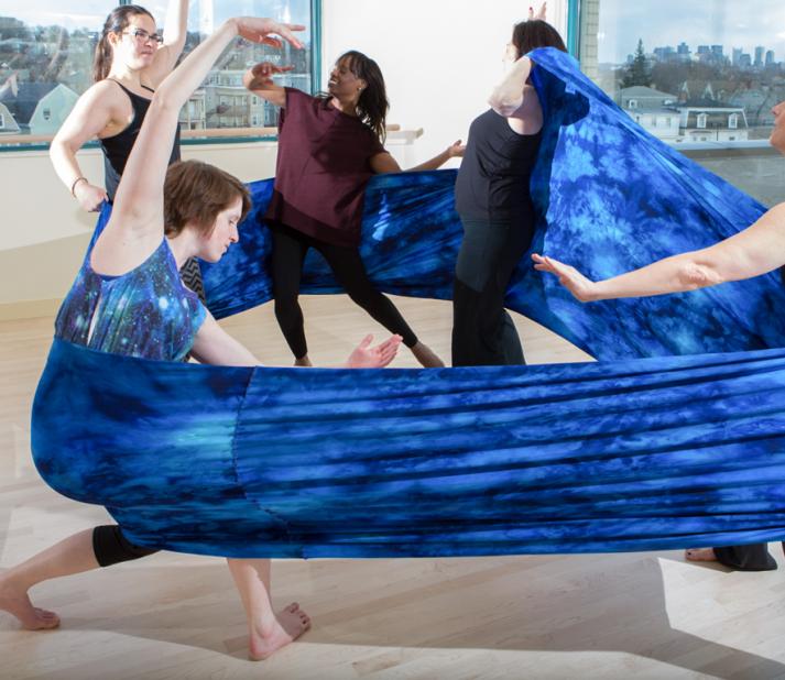 Five people pose within a large fabric wrap