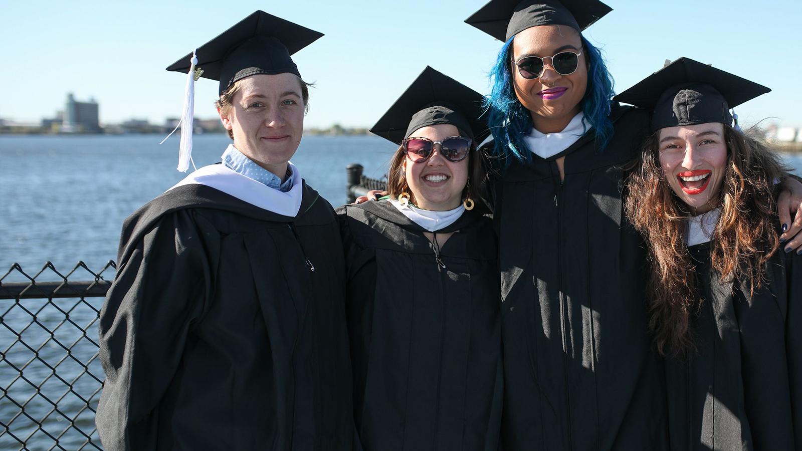 Lesley University smiling graduates by the water in undergraduate commencement