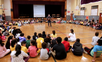 David Levine plays the guitar in front of a group of children