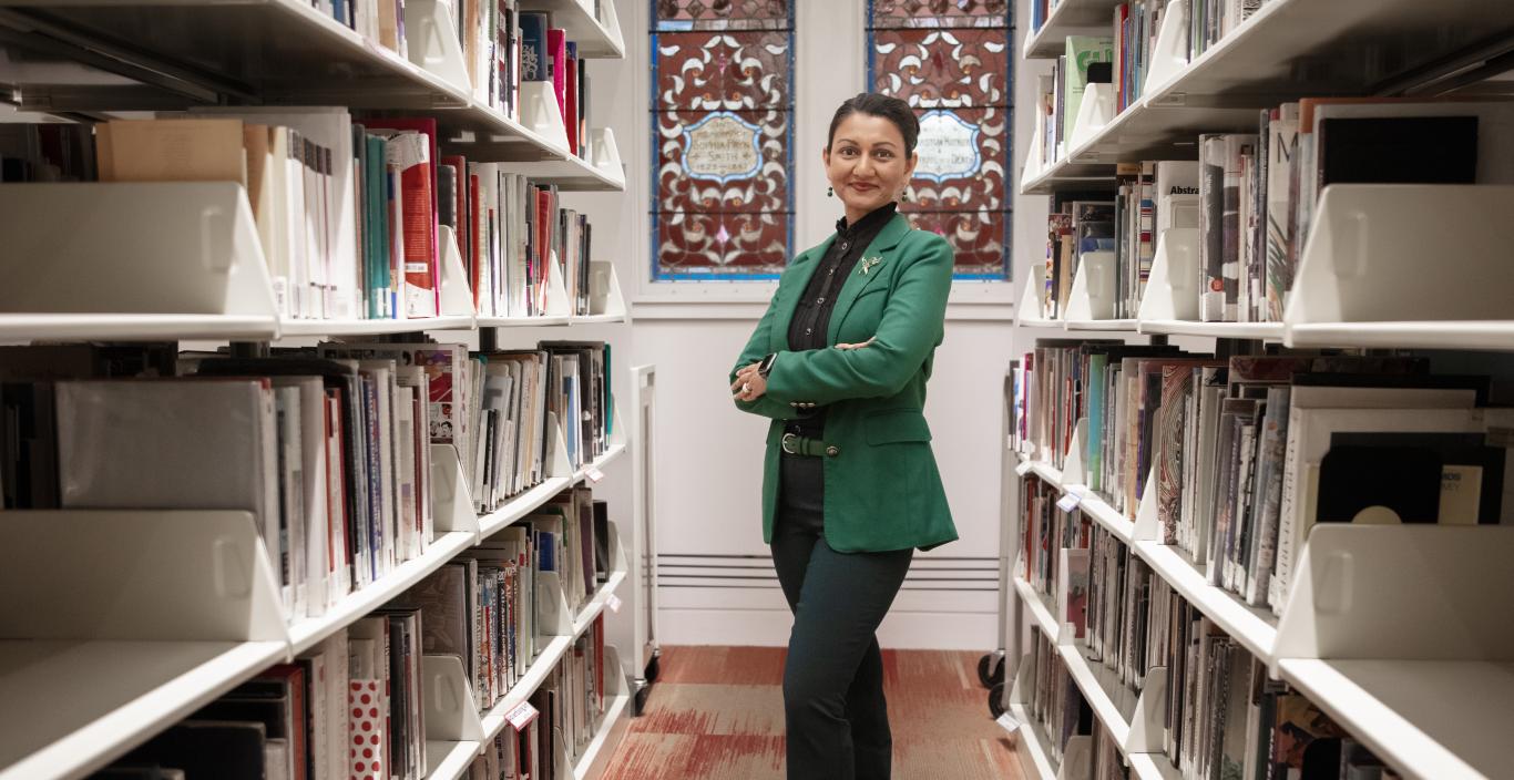 Gloria Noronha standing among the stacks in the library
