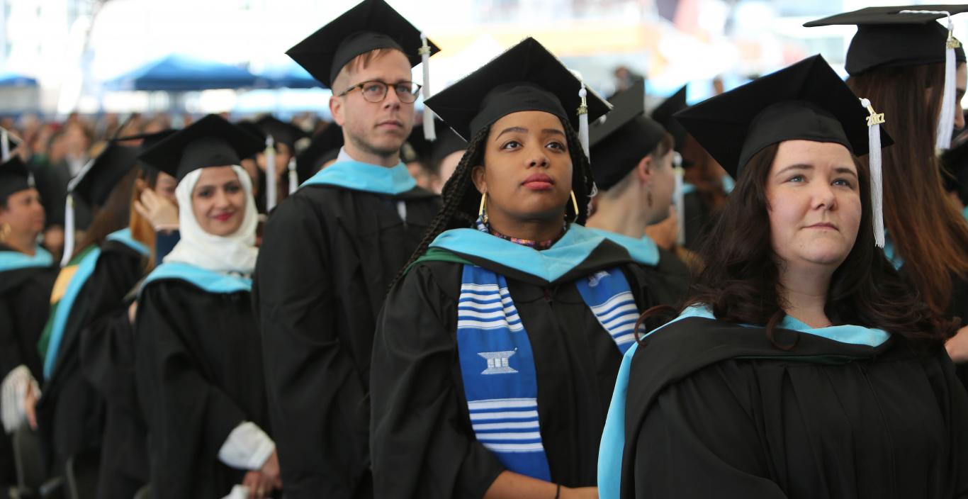 Graduate students stand at commencement