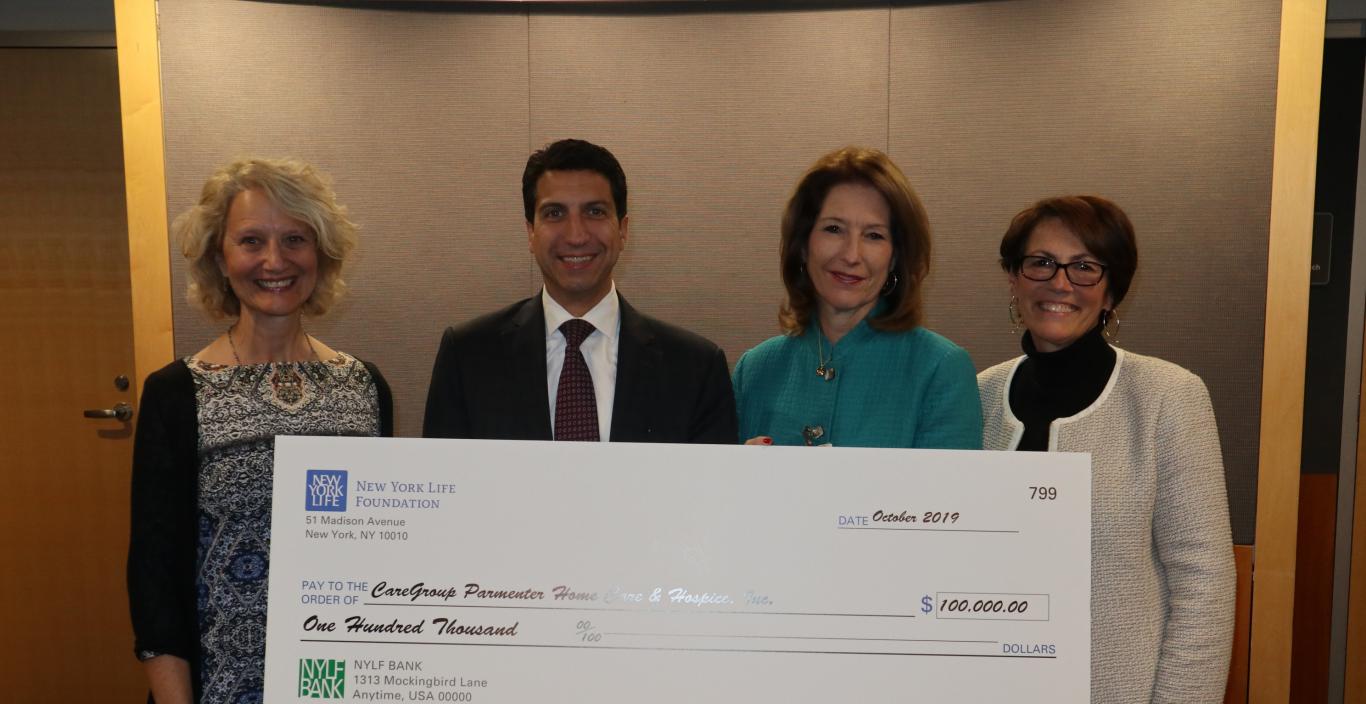 Photo of four people holding a large check from New York Life Foundation for $100,000.