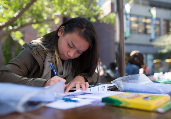female student filling out a form on a table outside
