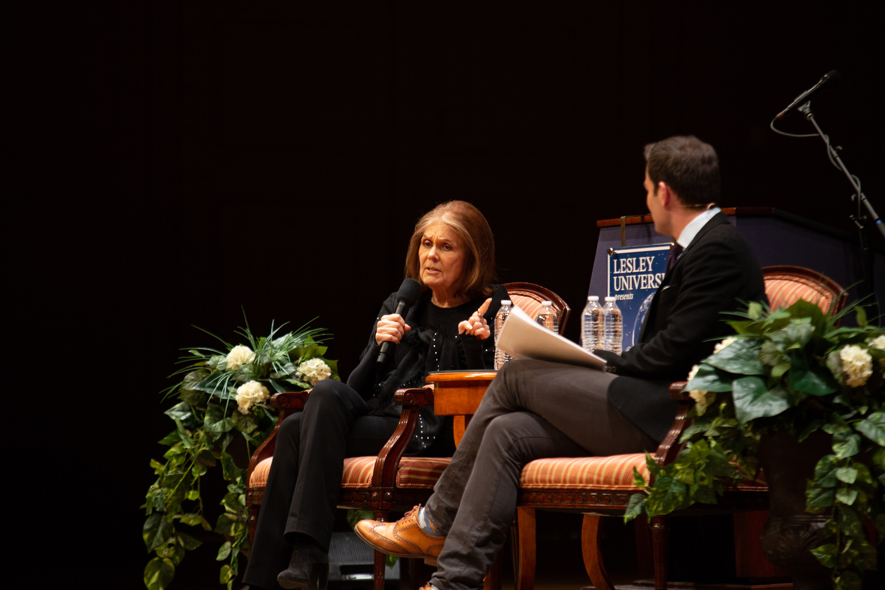 Gloria Steinem talks while seated next to Jared Bowen