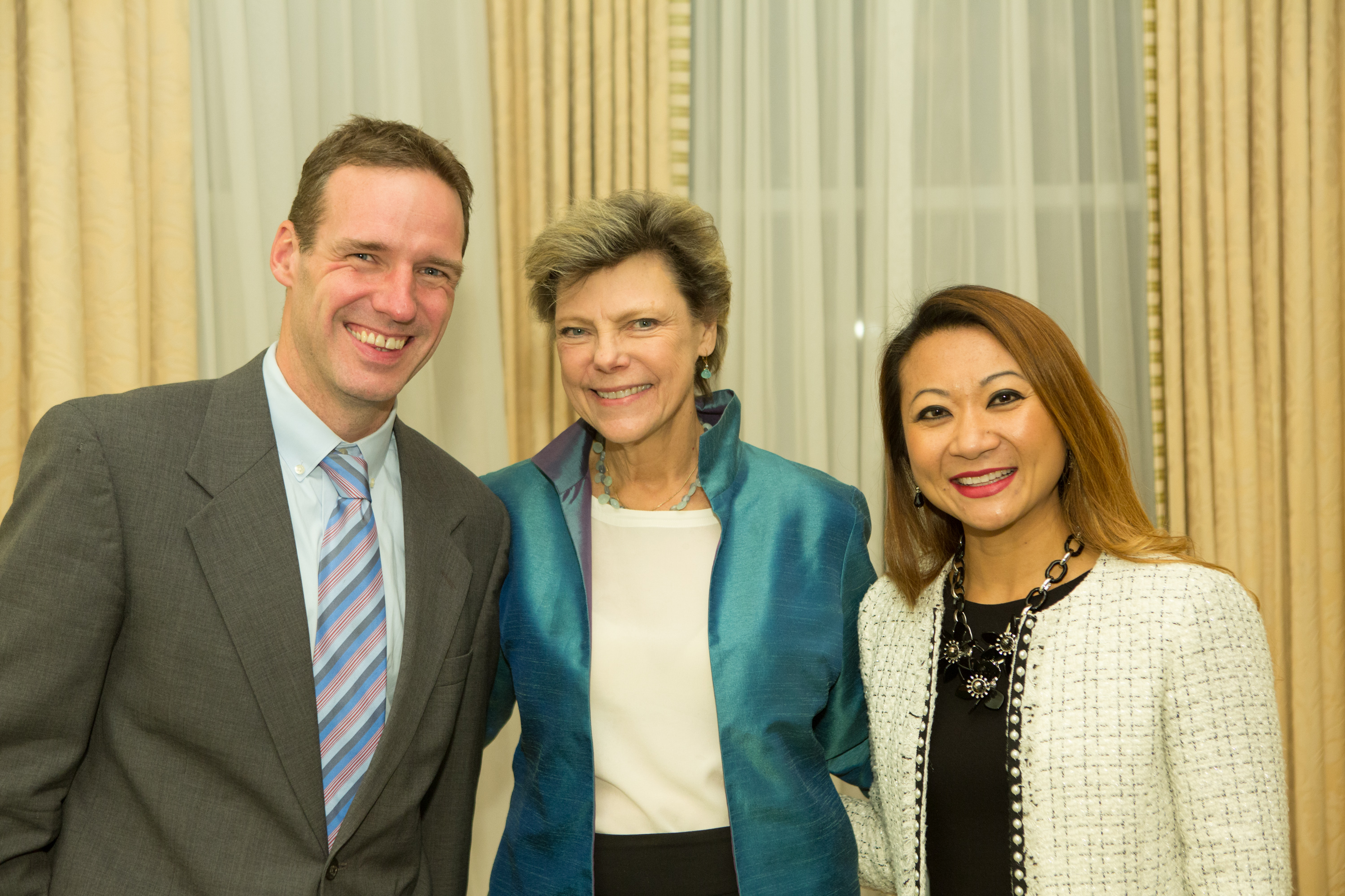 Tom Malone and Bopha Malone stand on either side of Cokie Roberts. All are smiling.