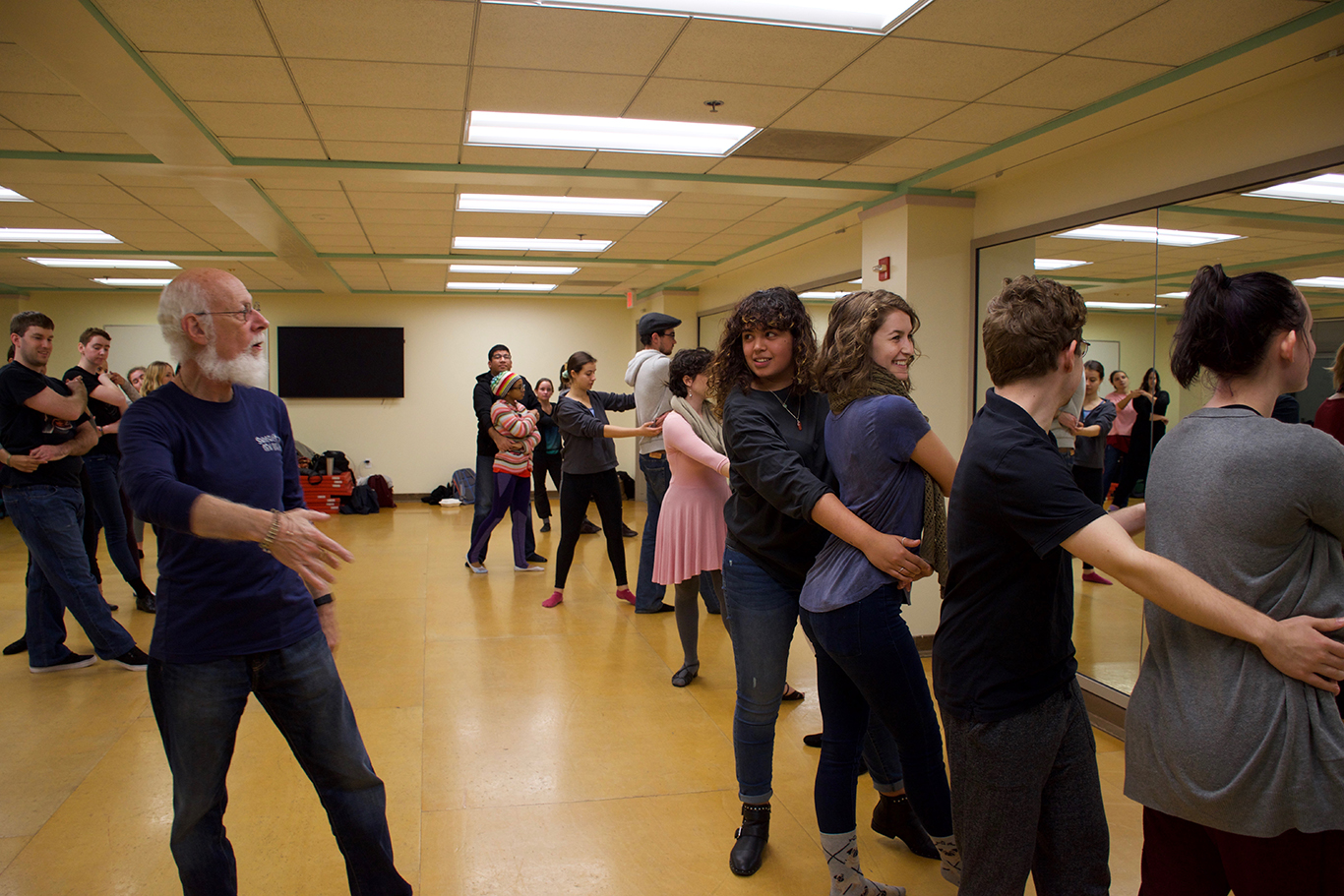 Professor shows students correct body placement during swing dance class in a dance studio.
