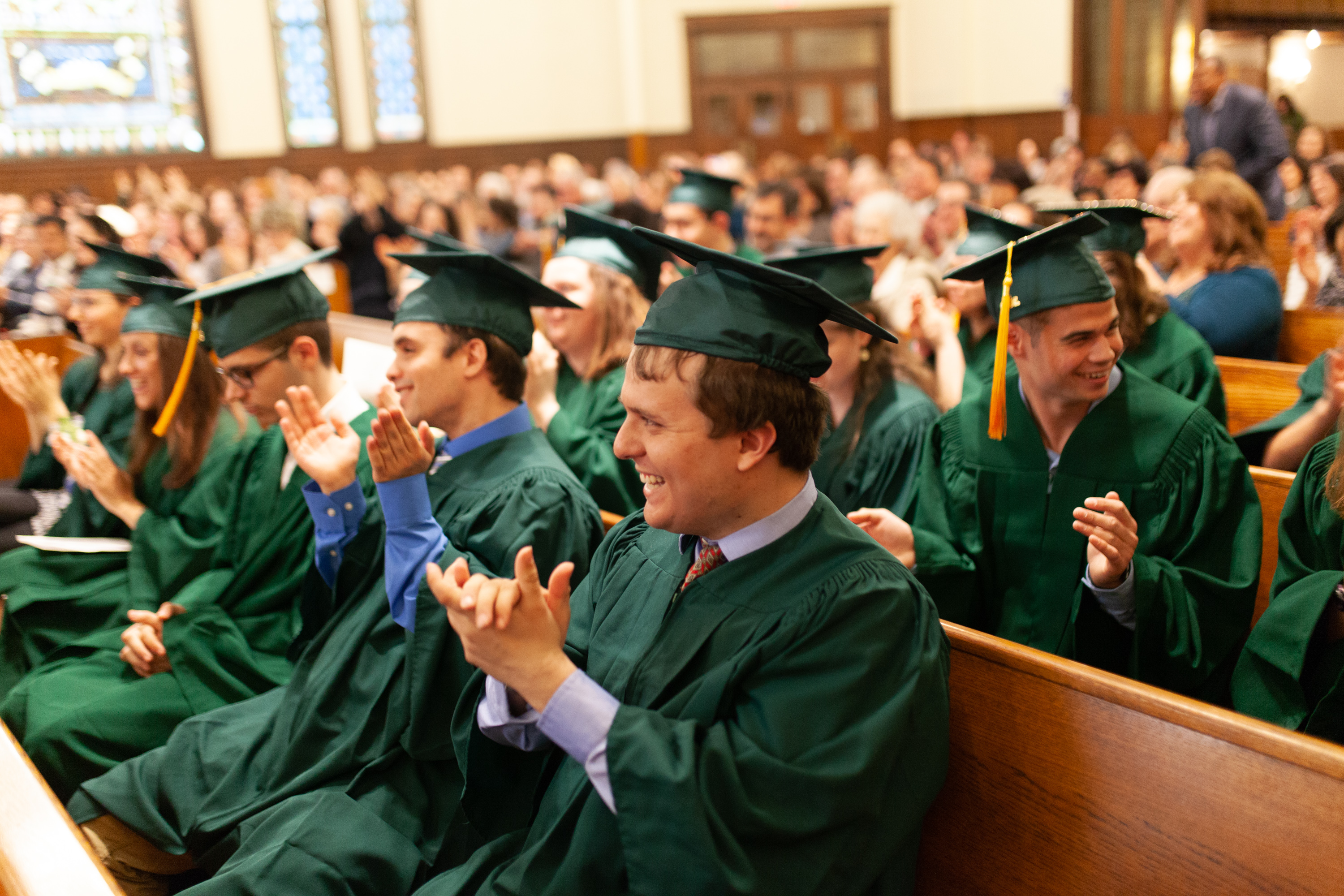 Graduates clap from the pews
