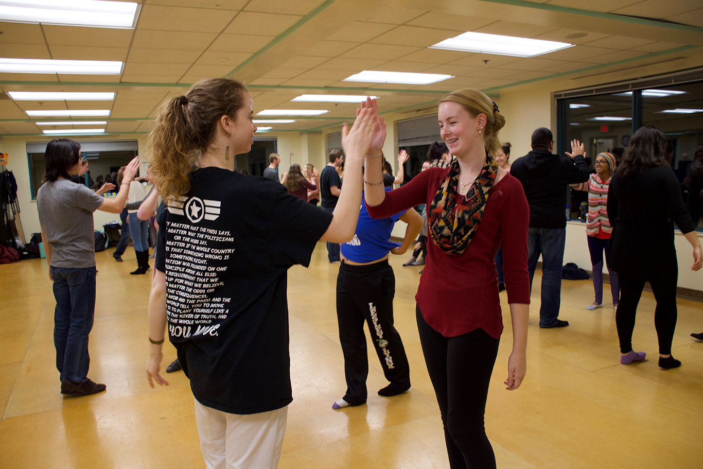 Students high-five each other in a dance studio during dance class.