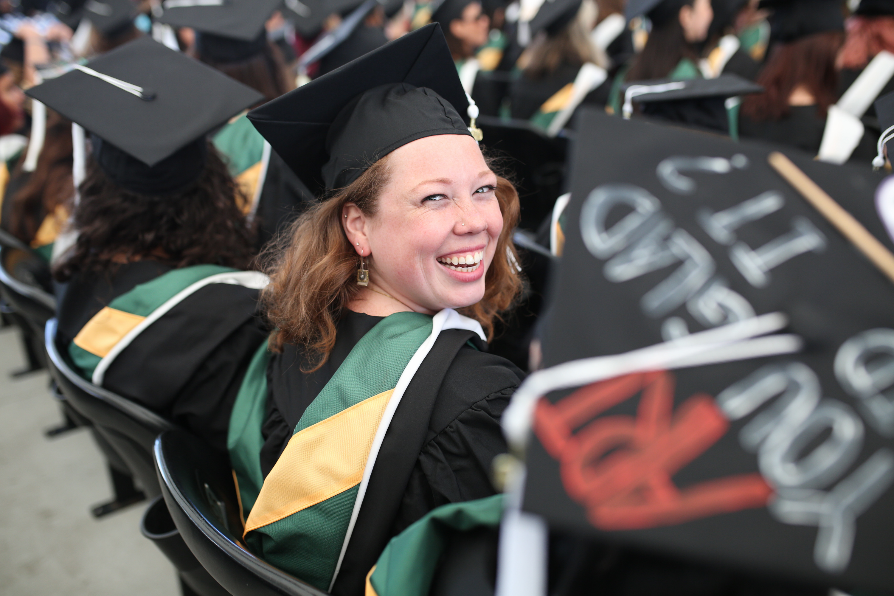 Female graduate looking back over her shoulder and smiling in the aisle.
