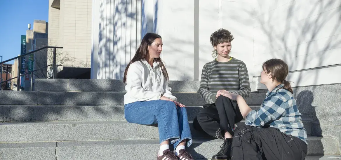 Three students sitting talking on outdoor steps