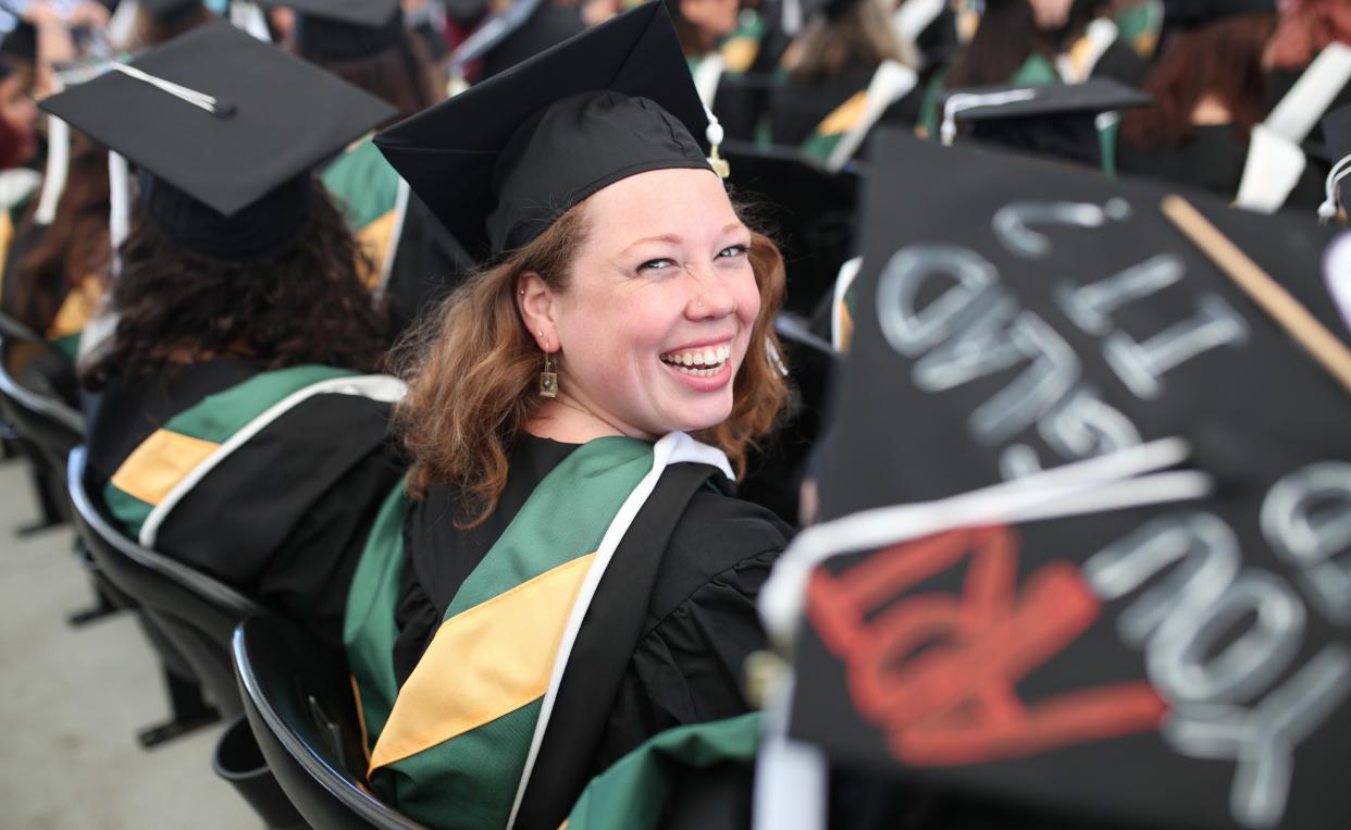 Female graduate looking back over her shoulder and smiling in the aisle.