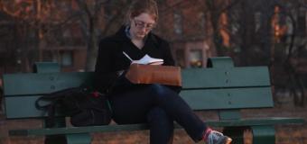 Julia Leef sitting on a bench writing on an autumn day.