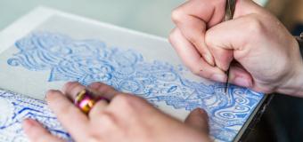 Hands etching a blue design