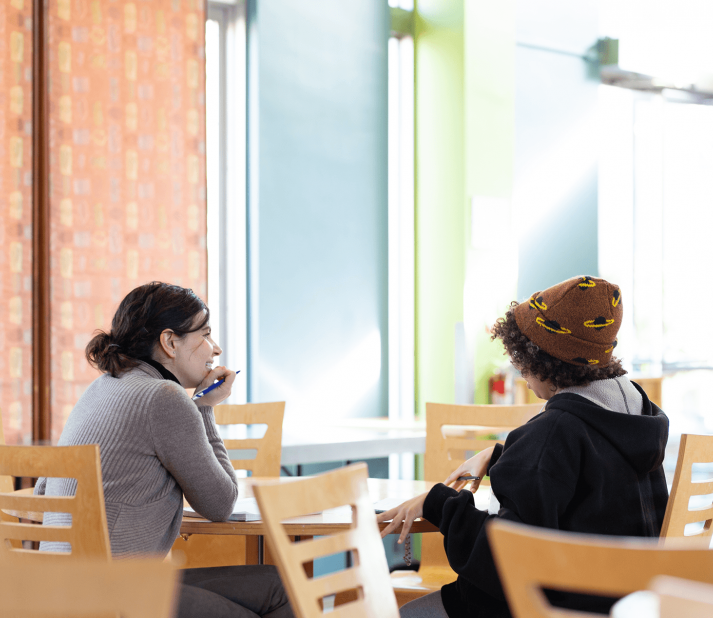 Two people speak at a table in Washburn dining hall.