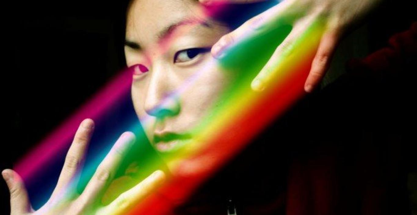 Artistic photo of Noel King with hands around face and prism over her fingers