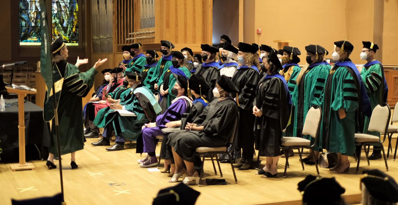 president and doctoral graduates standing on stage