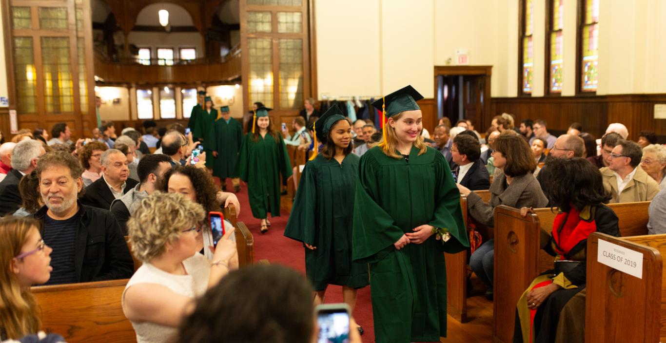 Students in cap and gown proceed into the church.