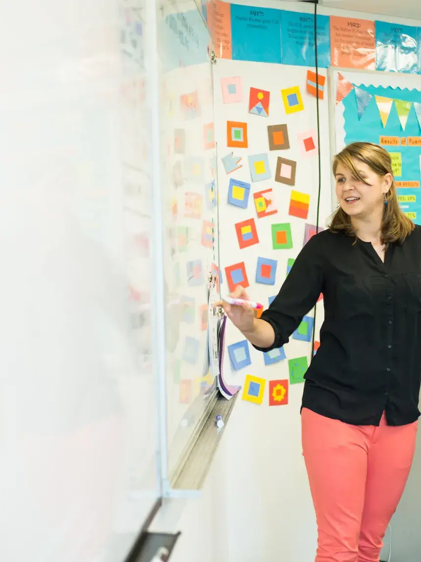 Sydney wearing orange pants and black shirt writing on white board